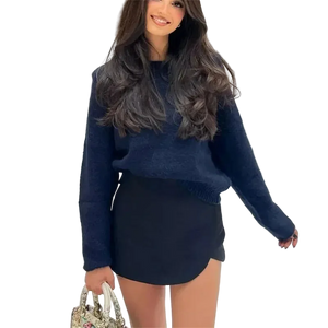 Woman wearing a blue sweater and black skirt holding a patterned handbag.