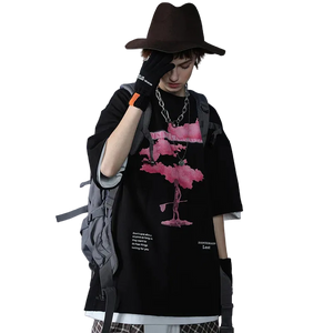 Person wearing a black outfit with a pink flamingo design, holding a phone, on a gray background