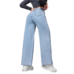Person wearing light blue jeans and white sneakers against a gray wall