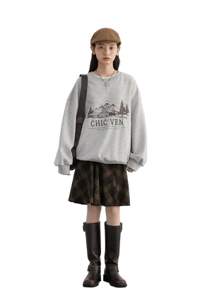 Person wearing a gray sweatshirt with text, plaid skirt, and brown boots on a white background