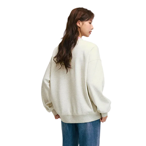 Person wearing a light-colored sweater and blue jeans on a plain background