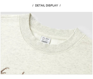 Close-up of a cream-colored sweater with a brand label on a light gray background