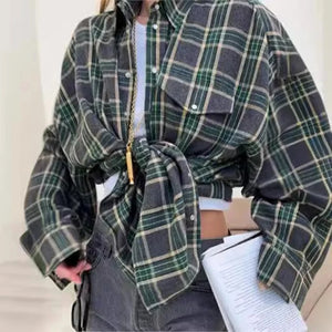 Person wearing a green and gray plaid shirt with a belt, holding a notebook.
