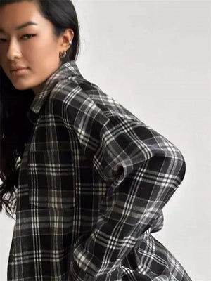Person wearing a plaid coat holding a pink magazine with a blurred background