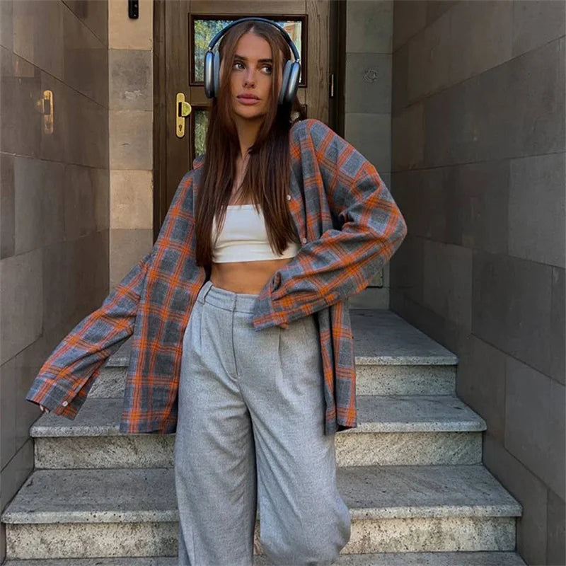 Woman standing on stone steps wearing a plaid shirt and headphones
