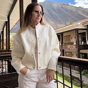 Woman in a white outfit standing on a balcony with mountains in the background