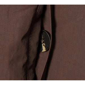 Close-up of a brown fabric with a button and zipper detail