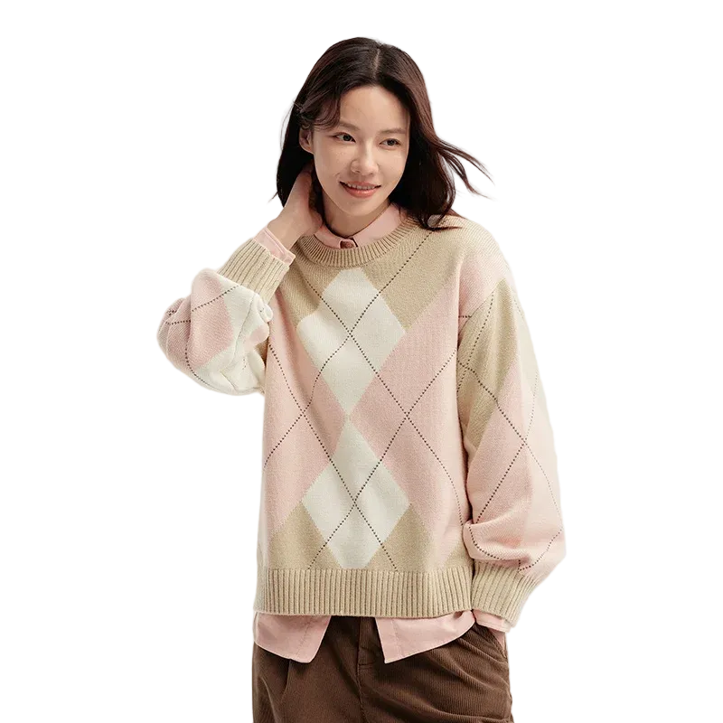 Woman wearing a pink and beige argyle sweater on a light background