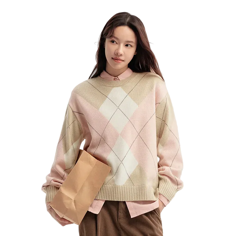 Woman wearing a pink and beige argyle sweater holding a brown paper bag on a light background