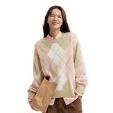 Woman wearing a pink and beige argyle sweater holding a brown paper bag on a white background