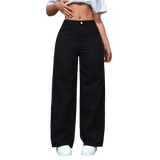 Person wearing black wide-leg pants and a white crop top against a gray wall.