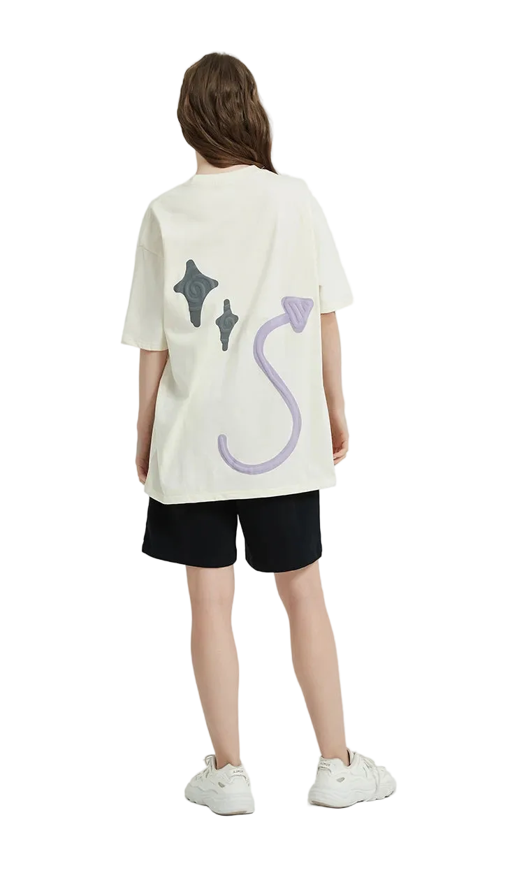 Person wearing a white oversized t-shirt with colorful designs on a plain background
