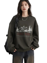 Person wearing a dark green sweatshirt with a graphic design and text, standing against a plain background.