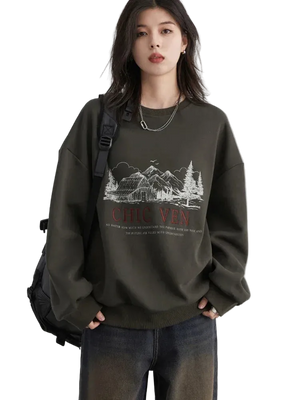 Person wearing a dark green sweatshirt with a graphic design and text, standing against a plain background.