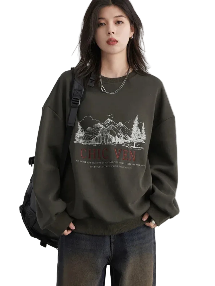 Person wearing a dark green sweatshirt with a graphic design and text, standing against a plain background.