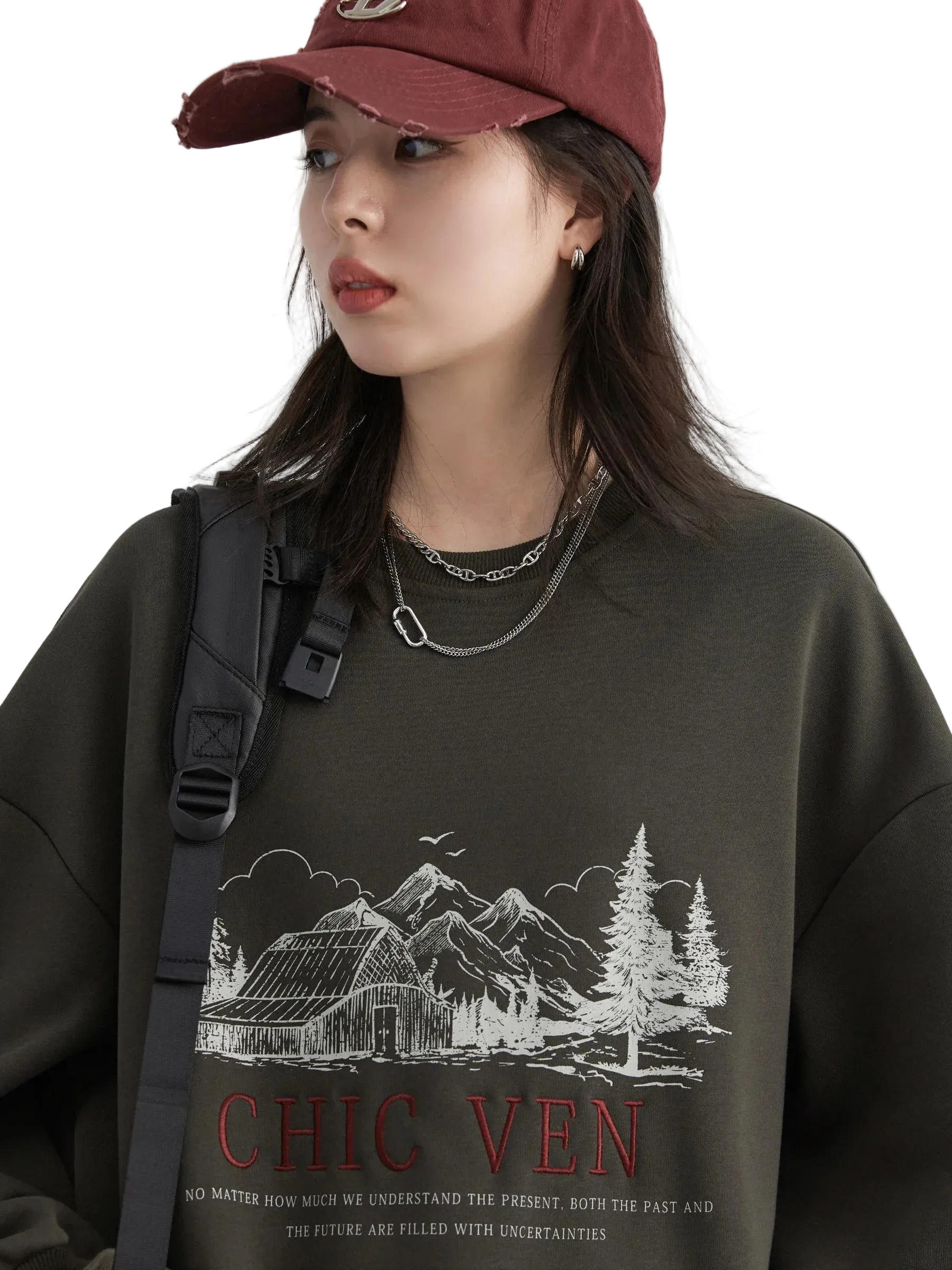 Person wearing a dark sweatshirt with a graphic design and text, standing against a plain background.