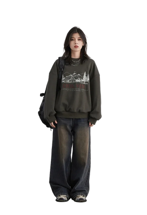 Person wearing a dark green sweatshirt with a graphic design and wide-leg jeans on a white background