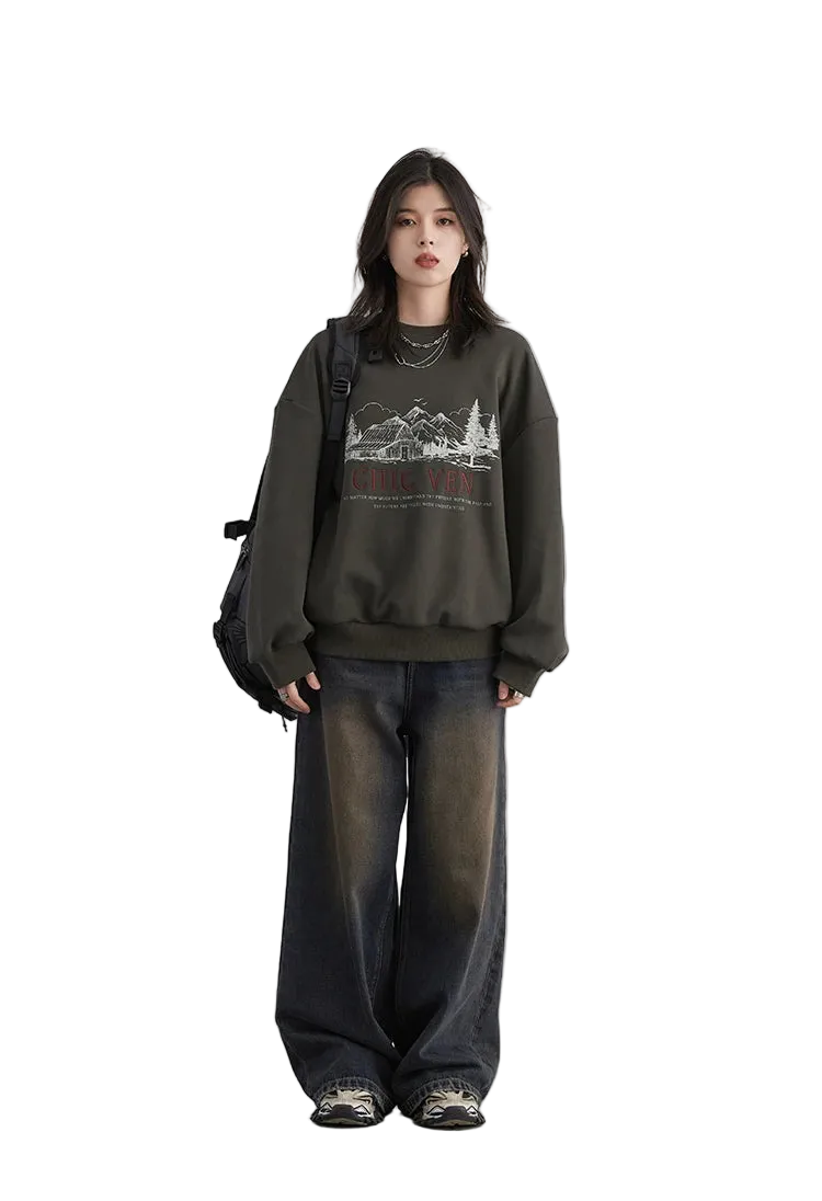 Person wearing a dark green sweatshirt with a graphic design and wide-leg jeans on a white background