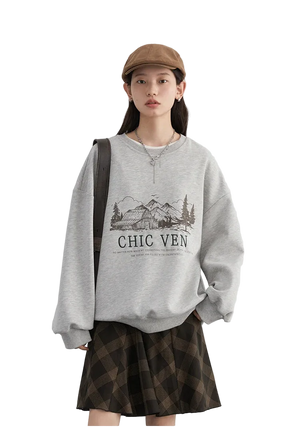 Person wearing a gray sweatshirt with a graphic design and text, standing against a plain background