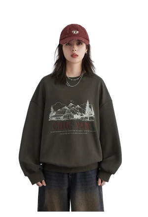 Person wearing a dark green sweatshirt with a graphic design and text, paired with a red cap on a light gray background.