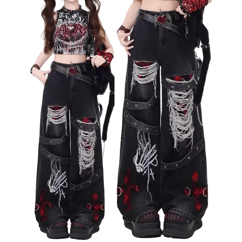 Black distressed jeans with red and white designs worn by a model on a white background