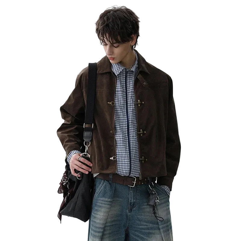 Man wearing a brown jacket with a checkered shirt and jeans, holding a black bag.