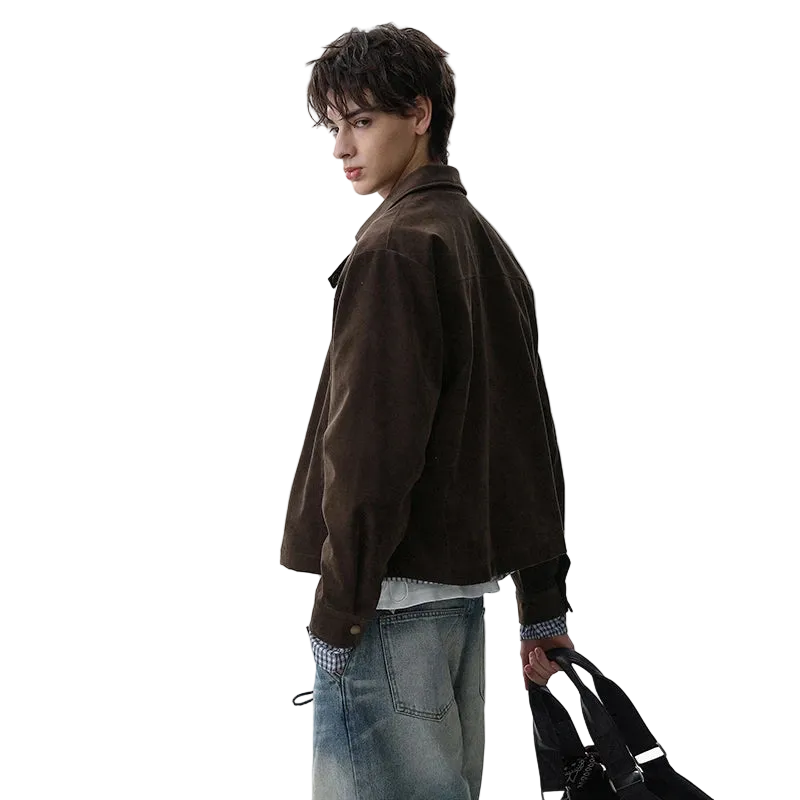Person wearing a brown jacket and blue jeans holding a black bag on a white background