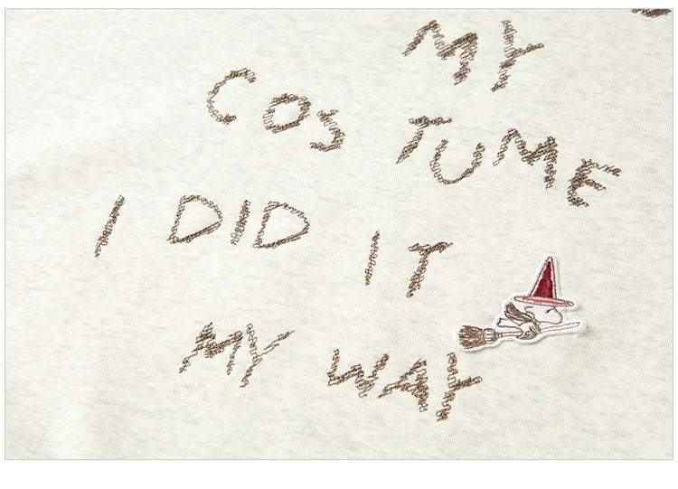 Text on sand with a broom and witch hat graphic, indicating a Halloween costume theme.