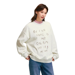 Person wearing a white sweatshirt with text, standing against a plain background