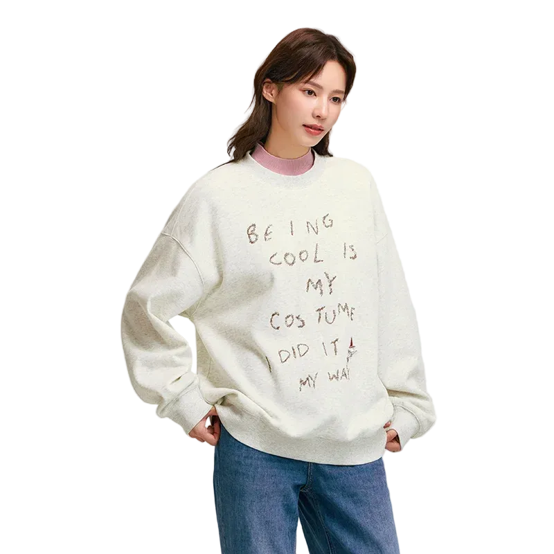 Person wearing a white sweatshirt with text, standing against a plain background