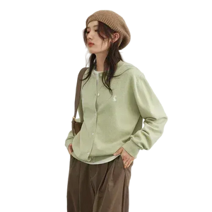 Person wearing a light green shirt and brown pants with a beige beanie on a white background
