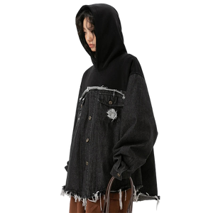 Person wearing a black hoodie and distressed denim jacket on a white background