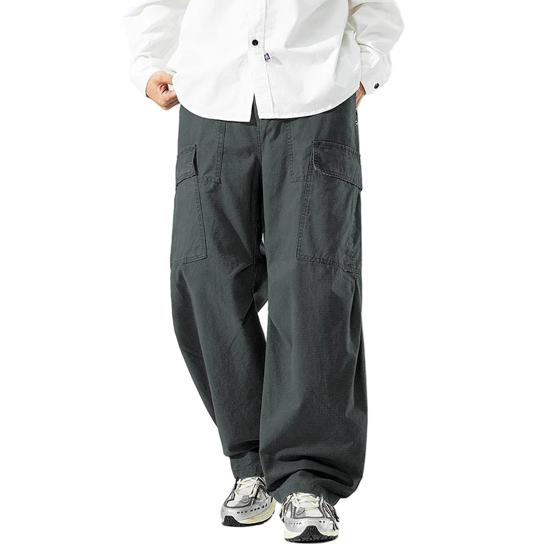 Person wearing gray cargo pants and a white shirt on a white background