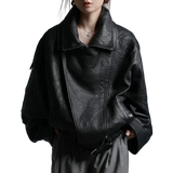 Person wearing a black leather jacket against a gray background
