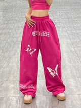 Pinkfarbene Jogginghose mit weitem Bein und Bufferfly-Muster im Y2K-Stil