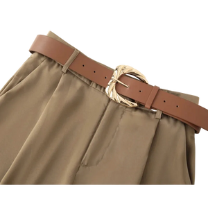 Brown belt with a gold buckle on beige pants against a white background