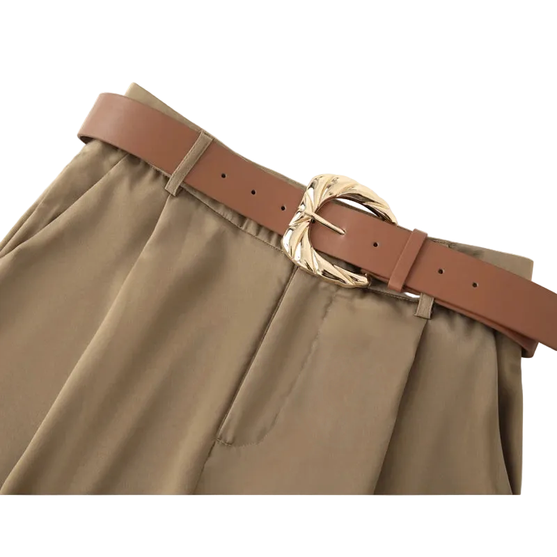 Brown belt with a gold buckle on beige pants against a white background