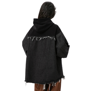 Person wearing a black distressed denim jacket on a white background