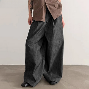 Person wearing wide-leg dark jeans and a brown shirt against a plain background