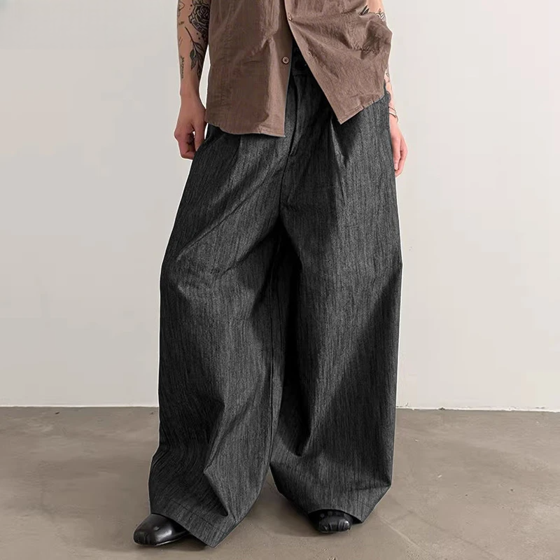 Person wearing wide-leg dark jeans and a brown shirt against a plain background