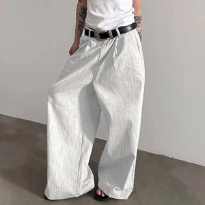 Person wearing white wide-leg pants and a white top against a plain background