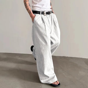 Person wearing white wide-leg pants and a white shirt against a plain background