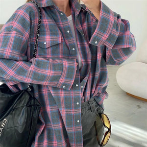 Person wearing a plaid shirt with a black bag and sunglasses on a light background