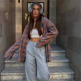 Woman standing on stone steps wearing a plaid shirt and headphones