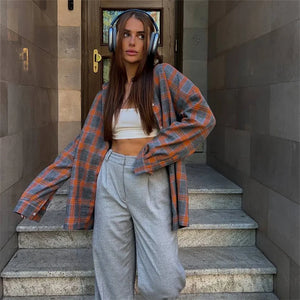 Woman standing on stone steps wearing a plaid shirt and headphones