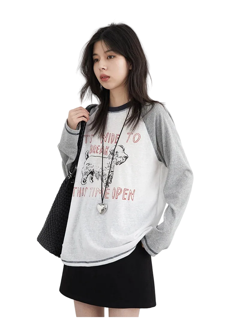 Woman wearing a gray and white sweatshirt with text and graphics, holding a black bag on a white background