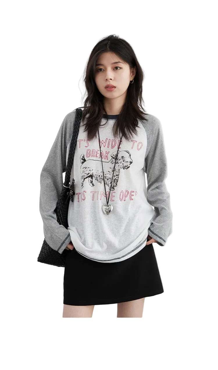 Woman wearing a gray and white graphic t-shirt with text and a graphic design.