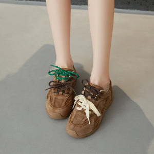 Brown sneakers with colorful laces on a neutral background