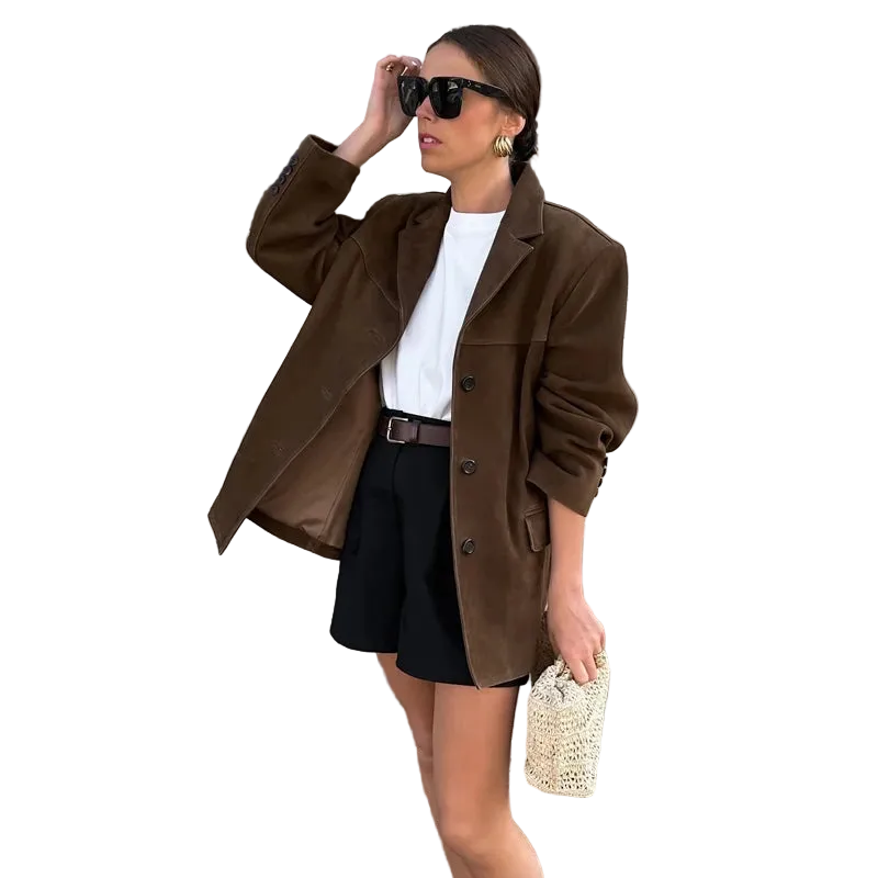 Woman in a brown coat and black skirt standing on steps with decorative columns in the background