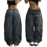 Two views of dark blue jeans with embroidery on a plain background